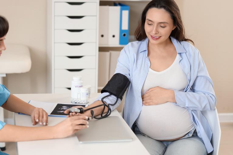A pregnant woman is getting her blood pressure checked by a healthcare provider.